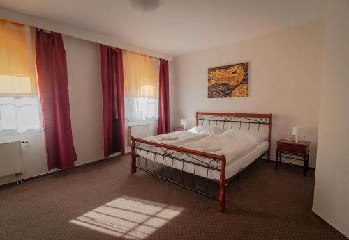 a bedroom with a bed and red curtains at Hotel Garni Orlova in Orlová