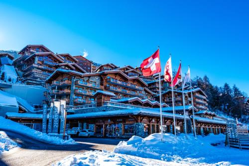 a lodge in the snow with flags in front of it at Nendaz 4 Vallées & SPA 4* Superior in Nendaz