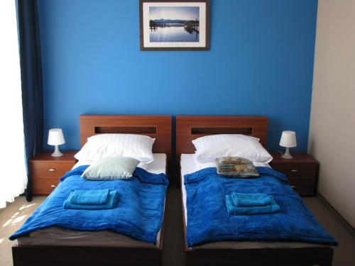 two beds in a bedroom with a blue wall at Willa Akacja in Gdynia