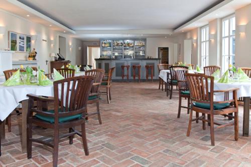 a dining room with tables and chairs and a kitchen at Gut Sarnow - Hotel, Restaurant und Reitanlage in Schorfheide