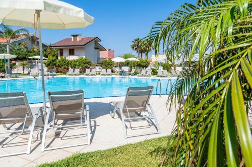 a group of chairs and umbrellas next to a pool at Capo Peloro Hotel in Torre Faro