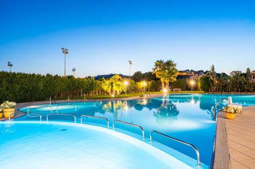 a large swimming pool with blue water at dusk at Capo Peloro Hotel in Torre Faro