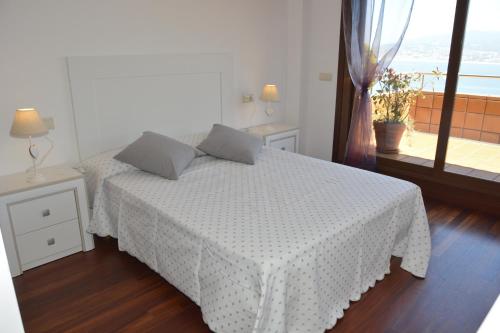 Cama blanca en habitación con ventana en EXCLUSIVO APARTAMENTO CON VISTAS ESPECTACULARES, en Baiona