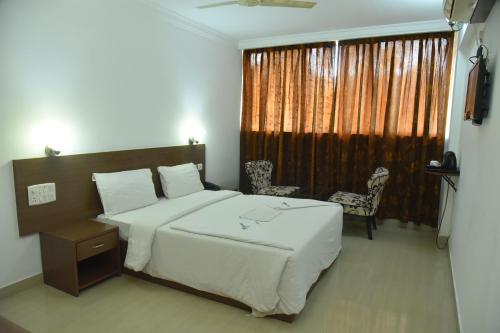 a bedroom with a large bed and a window at Emporium Hotel in Mangalore