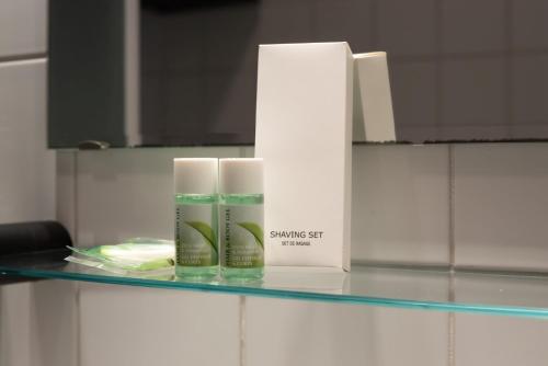 a shelf with two bottles of sunscreen on it at Hôtel Mosa in Hermalle-sous-Argenteau