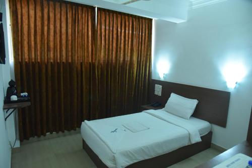 a bedroom with a bed and a large window at Emporium Hotel in Mangalore