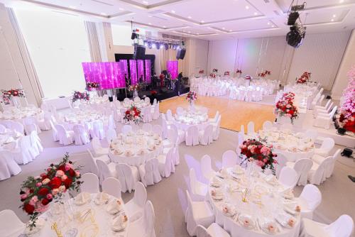 a banquet hall with white tables and white chairs at Resident City Hotel in Almaty