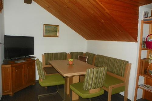 a dining room with a table and chairs and a television at Ferienwohnung am Weissenstädter See in Weißenstadt