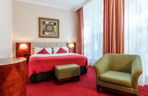 a hotel room with a red bed and a chair at Hotel Amaris Bremerhaven in Bremerhaven