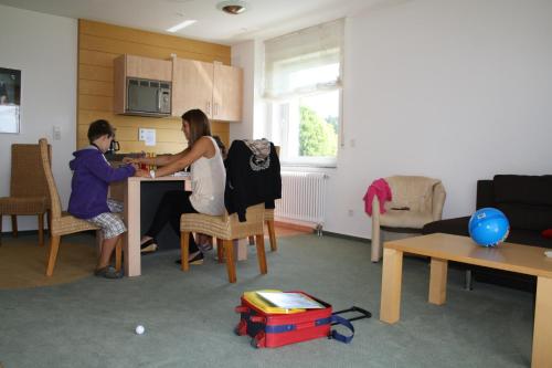 a man and woman sitting at a table in a living room at Apartmenthaus SportCHALET in Bad Dürrheim