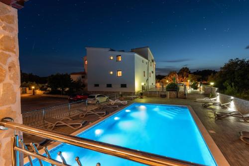 a swimming pool in front of a house at night at Apartments Karen in Vinišće