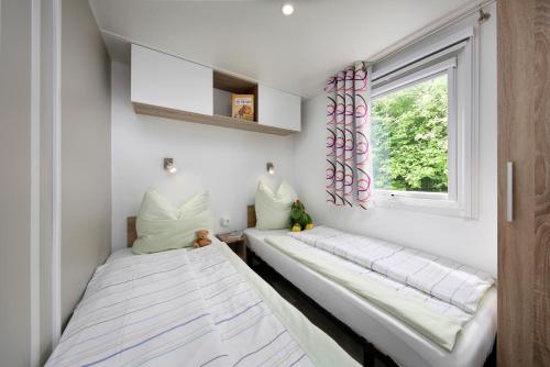 a small bedroom with two beds and a window at KNAUS Campingpark Hennesee in Meschede