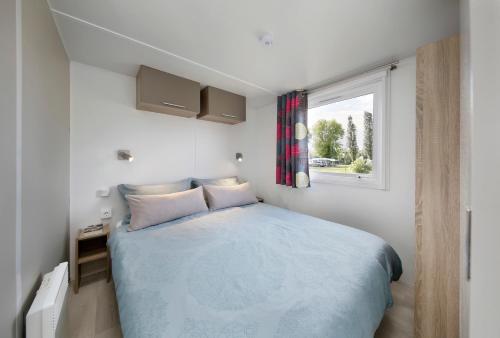 a small bedroom with a bed and a window at KNAUS Campingpark Hennesee in Meschede