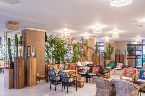 a lobby with chairs and tables and potted plants at Capo Peloro Hotel in Torre Faro