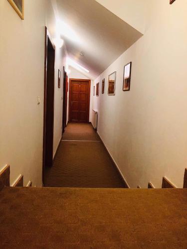 a long hallway with a table and a wooden door at Pensiunea Lucia in Sfântu-Gheorghe