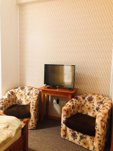 a room with two chairs and a tv on a table at Pensiunea Lucia in Sfântu-Gheorghe