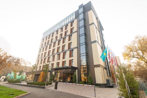 un grand bâtiment avec drapeaux devant lui dans l'établissement Resident City Hotel, à Almaty