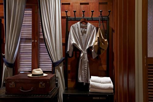 a room with a suit and a hat and a suitcase at Burasari Heritage Luang Prabang in Luang Prabang