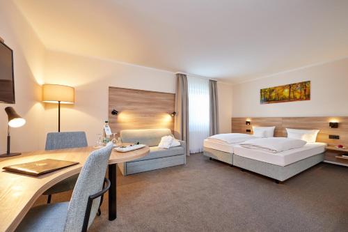 Una habitación de hotel con una cama, una mesa y un escritorio. en Hotel Linderhof, en Erfurt