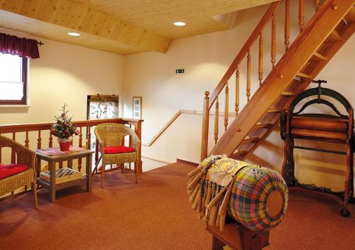 a living room with a staircase and a table and chairs at Pension zur Kurfürstin in Wolkenstein