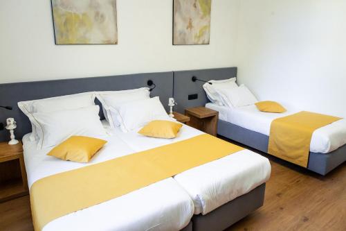 two beds in a hotel room with yellow pillows at Hotel Vila Pohorje in Slovenj Gradec