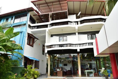 a large white building with a balcony on top at Relax Inn Hikkaduwa in Hikkaduwa