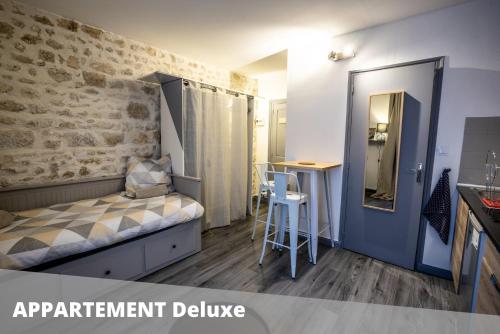 ポワティエにあるLes Apparts de Blossac Poitiersのベッド1台、テーブル(スツール付)が備わる小さな客室です。