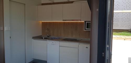 a kitchen with white cabinets and a sink and a microwave at Bungalows Portuondo parking gratuito in Mundaka