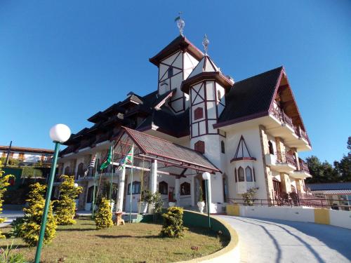 a large white building with a black roof at Hotel Nacional Inn Campos do Jordão in Campos do Jordão