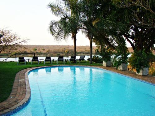 a large blue swimming pool with chairs and trees at Buhala Lodge in Malelane