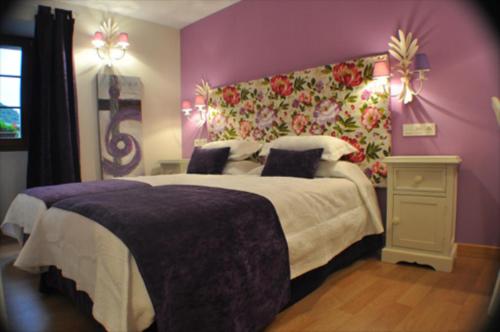 a bedroom with a large bed with a purple wall at El Rincón Del Convento in Oña