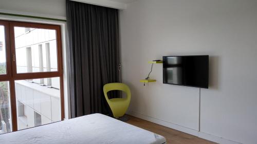 sypialnia z żółtym krzesłem i telewizorem na ścianie w obiekcie Baltic Beach View Porta Mare plaża w Dziwnówku