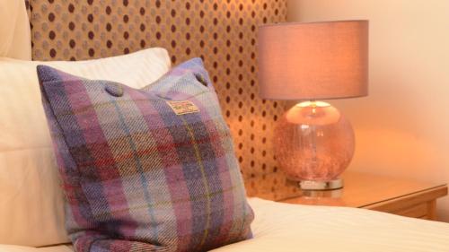 uma cama com uma almofada e um candeeiro sobre uma mesa em Torlinnhe Guest House em Fort William