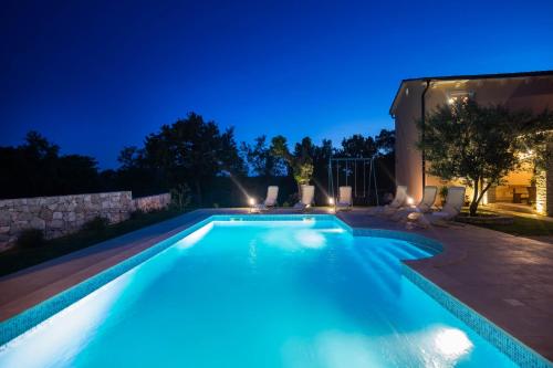 a swimming pool in a backyard at night at Beautiful villa Natura with pool in Labin in Labin