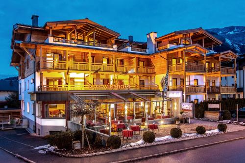 a large building with tables and chairs in front of it at Auhof Wirtshaus & Suiten in Kaprun
