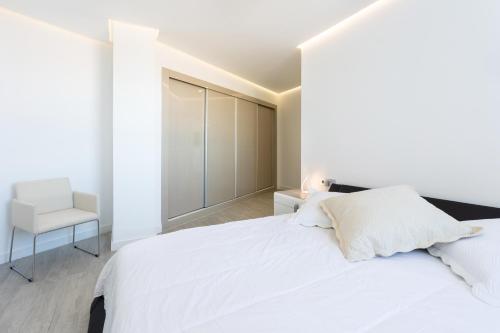 una camera da letto bianca con un letto bianco e una sedia di Oceanfront Rental ad Adeje