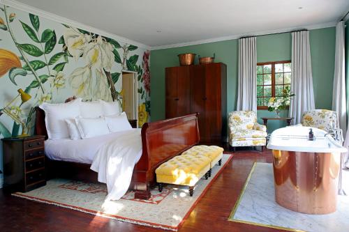 ein Schlafzimmer mit einem Bett und einer Bank darin in der Unterkunft Le Jardin Villa in Stellenbosch