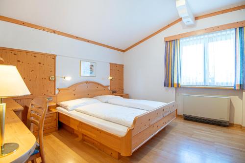 a bedroom with a wooden bed and a desk and a window at Haus Niederösterreich in Kirchberg in Tirol