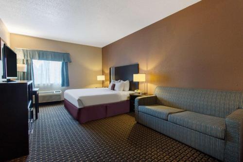 a hotel room with a bed and a couch at Ramada by Wyndham Glendale Heights/Lombard in Glendale Heights