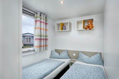 Habitación pequeña con 2 camas y ventana en KNAUS Campingpark Eckwarderhörne, en Eckwarderhörne