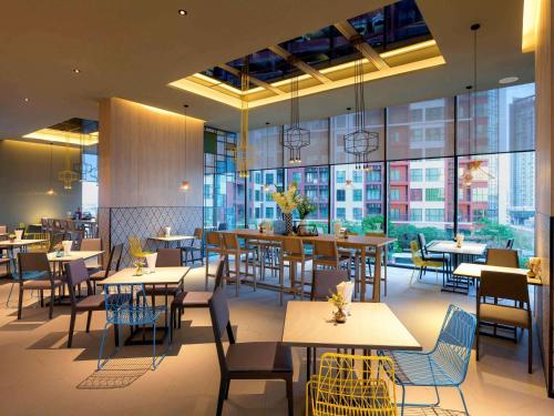 a restaurant with tables and chairs and large windows at ibis Styles Bangkok Sukhumvit Phra Khanong in Bangkok