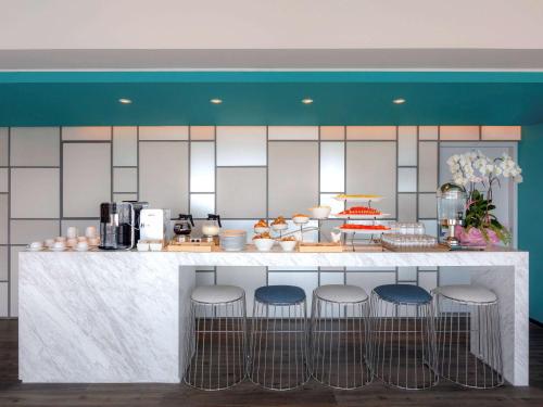 a kitchen with a counter with bar stools at ibis Styles Bangkok Sukhumvit Phra Khanong in Bangkok