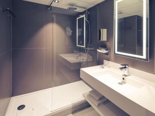 a bathroom with two sinks and a glass shower at Hotel Mercure Blois Centre in Blois