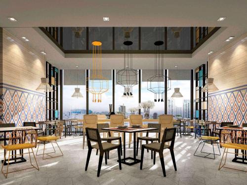 a dining room with a table and chairs and windows at ibis Styles Bangkok Sukhumvit Phra Khanong in Bangkok