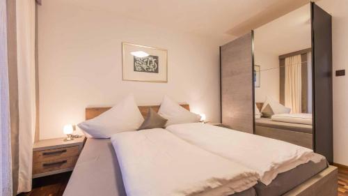 a bedroom with a large white bed and a mirror at Haus Auer Theresia in Telfes im Stubai
