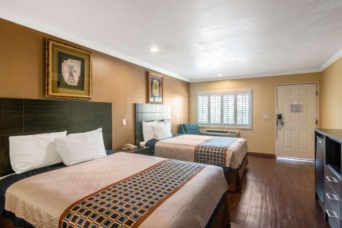 a hotel room with two beds and a television at Rodeway Inn Artesia Cerritos in Artesia