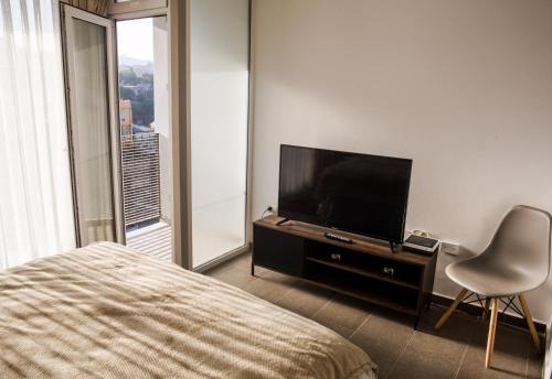 1 dormitorio con 1 cama, TV y silla en Loftbellavistavalparaiso, en Valparaíso