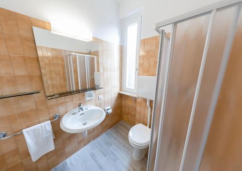 y baño con lavabo, aseo y espejo. en Appartamenti Pratone, en Garda