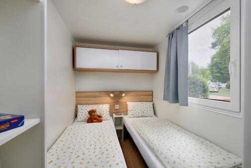 een kleine slaapkamer met 2 bedden en een teddybeer bij KNAUS Campingpark Dorum in Dorum Neufeld