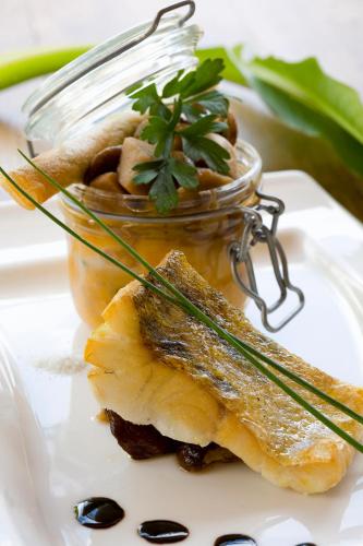 a glass jar of food on a white plate with food at Logis hotel les flots bleus in Beaulieu-sur-Dordogne